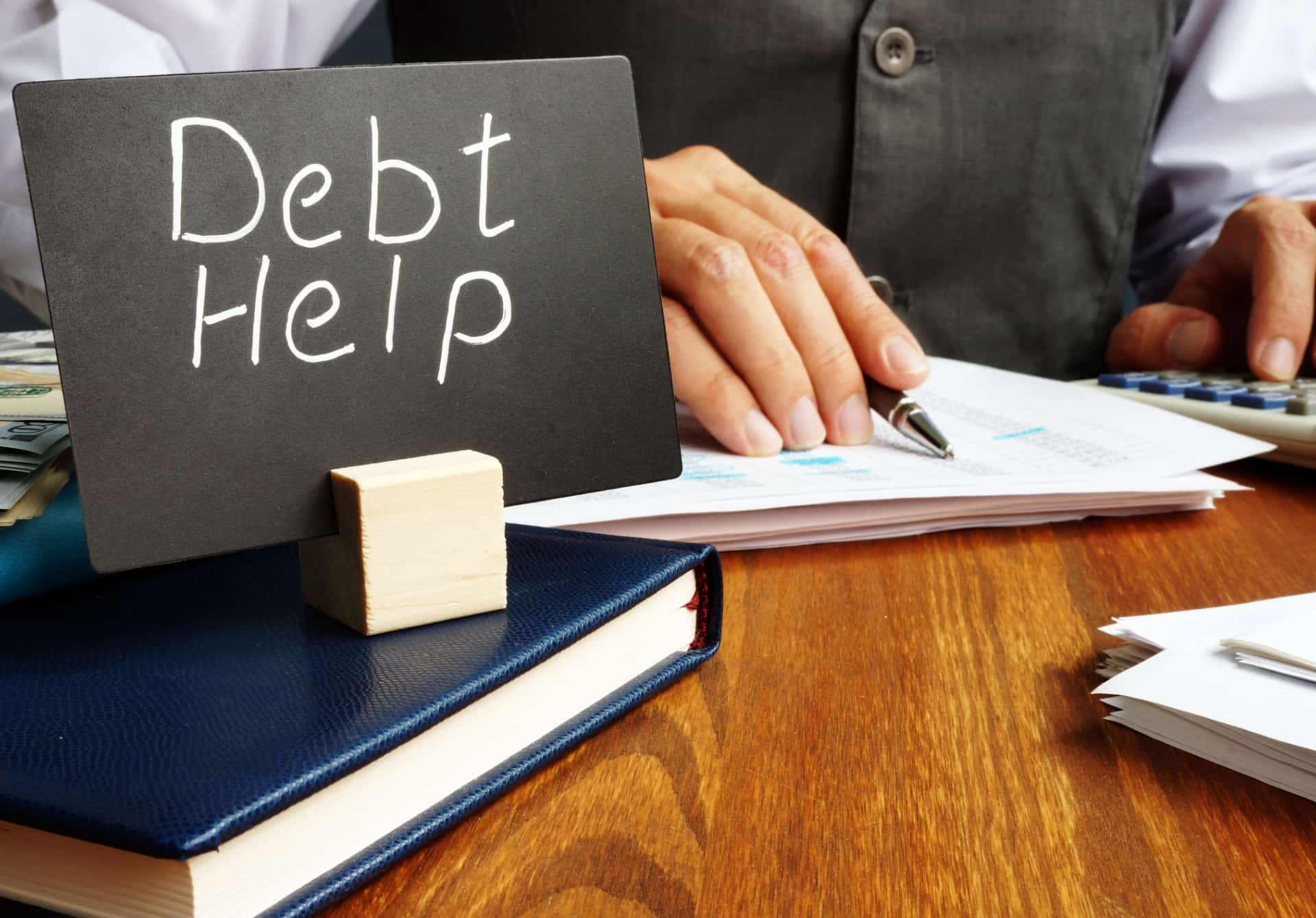 Debt Help sign on table of business person with documents.